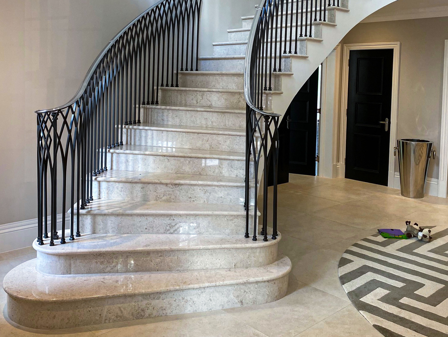 Curved staircase clad in marble with iron balustrades
