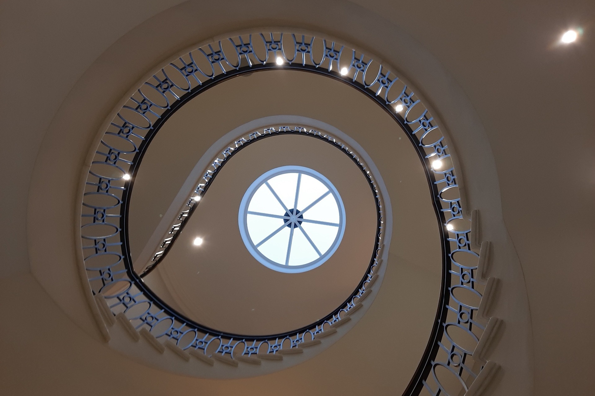Close up of skylight with helical concrete stair with iron balustrades