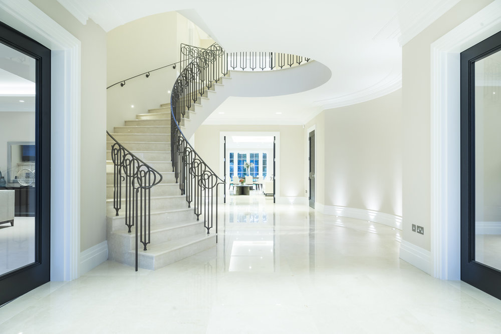 Custom home curved stairs with marble flooring and bespoke balustrade