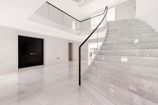 Marble clad curved staircase with glass handrail