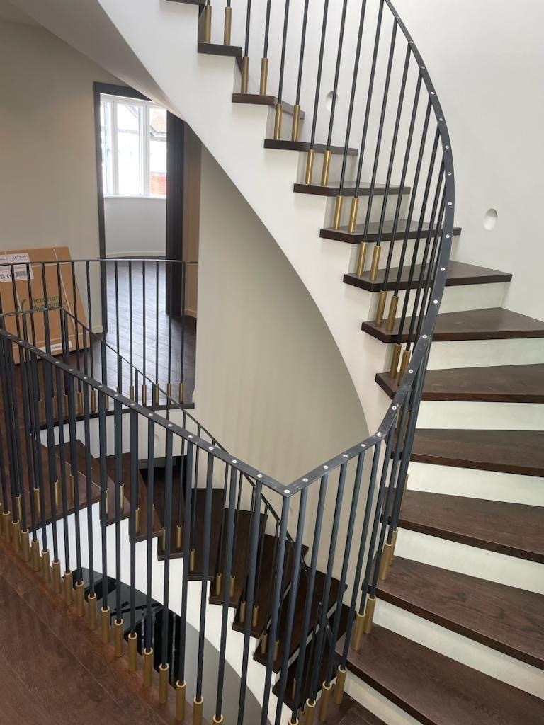 Ultra-modern curved staircase with attached handrails and timber treads
