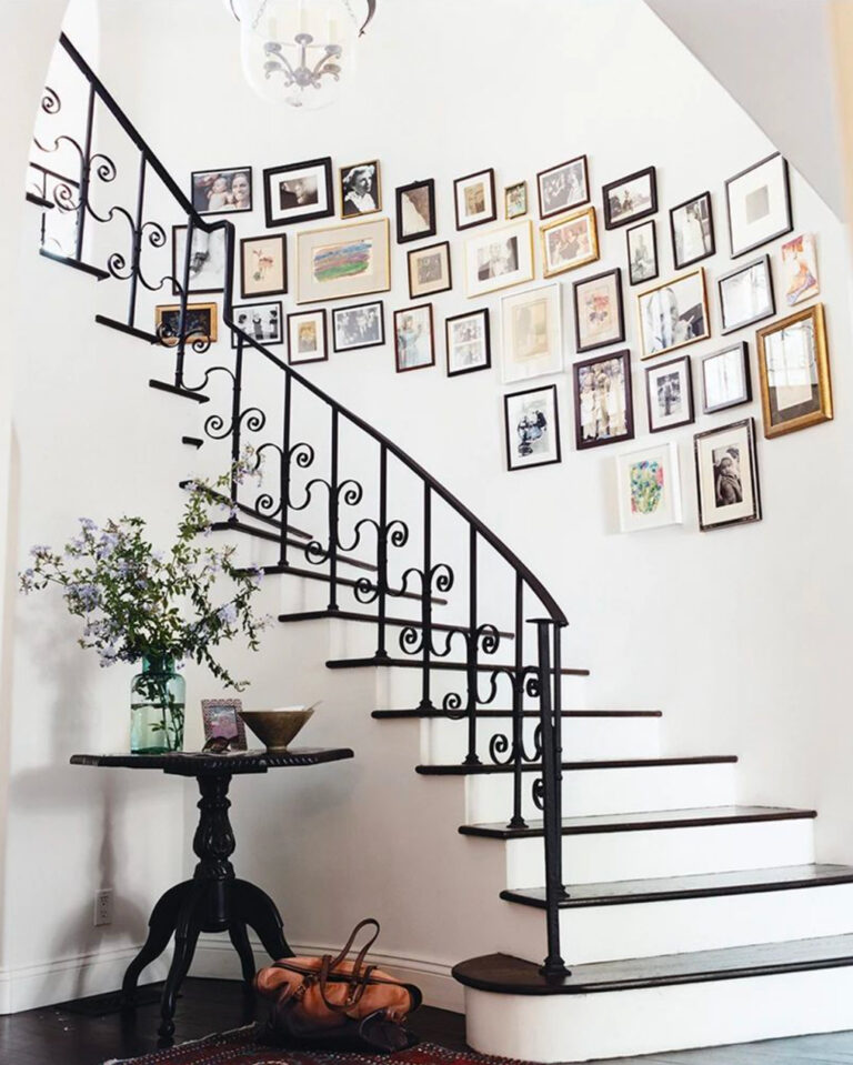 White curved staircase with photo gallery and table