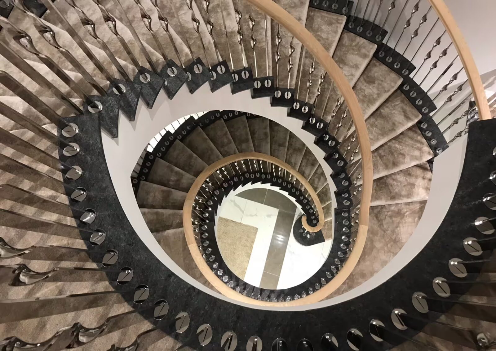 Curved helical staircases clad with luxury carpet and timber handrail