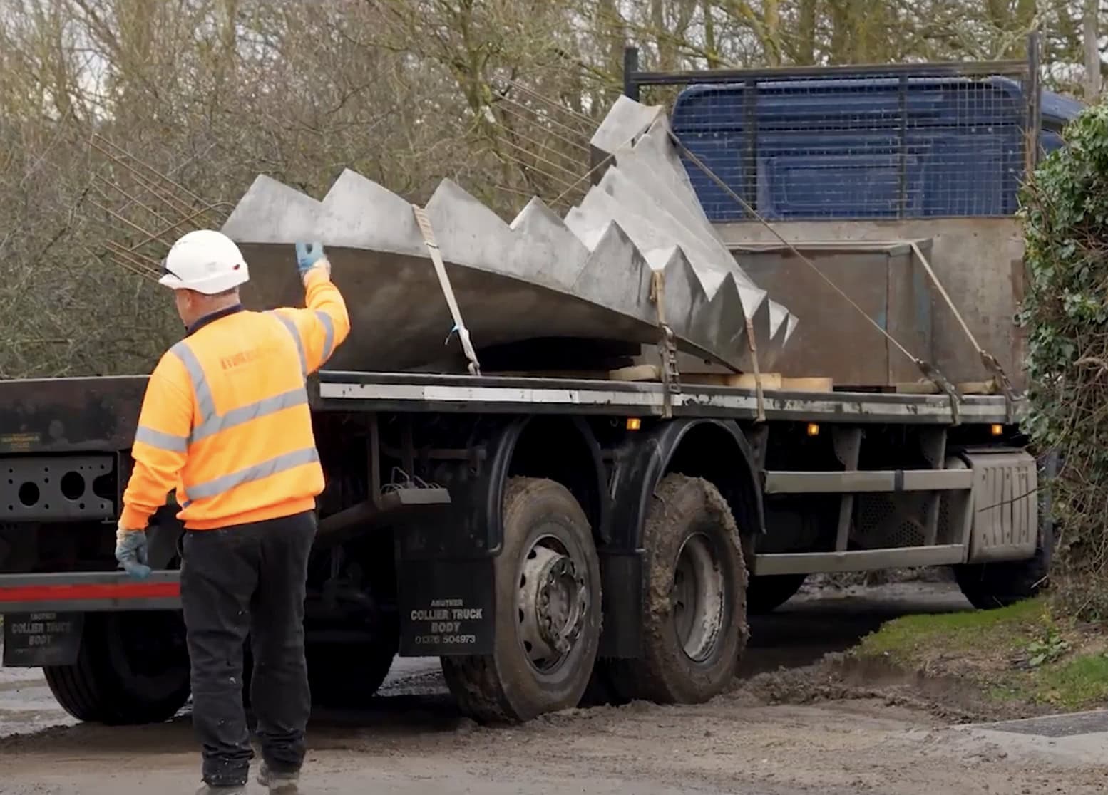 Construction worker guides delivery lorry with curved concrete staircase onto building site