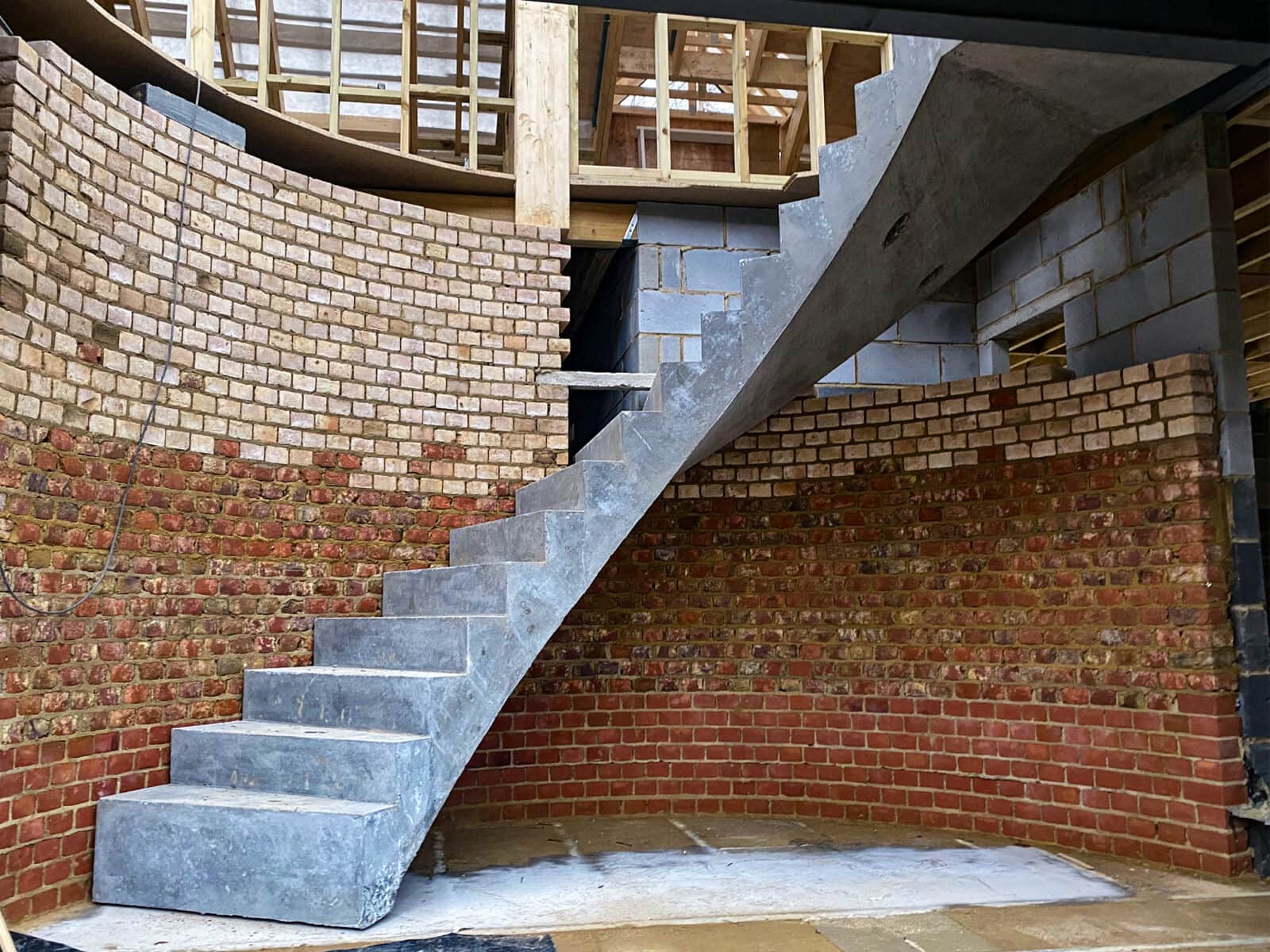 Curved precast concrete staircase built in to curved brick wall for support