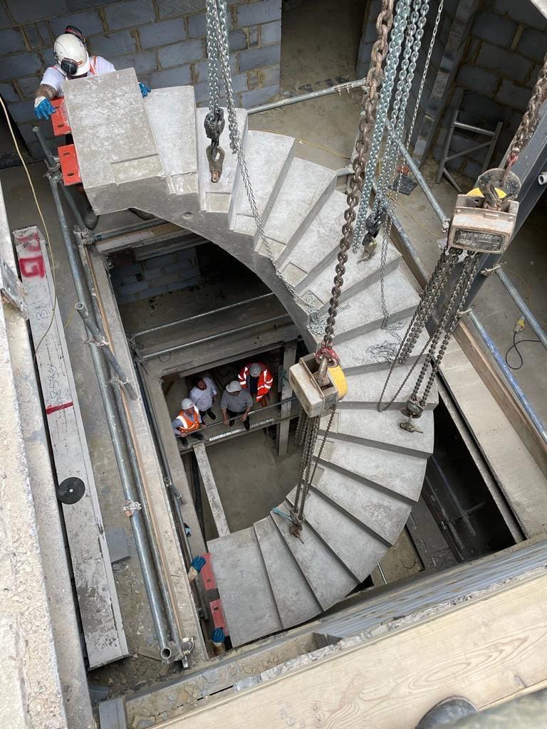 Helical precast concrete staircase craned into position with chains
