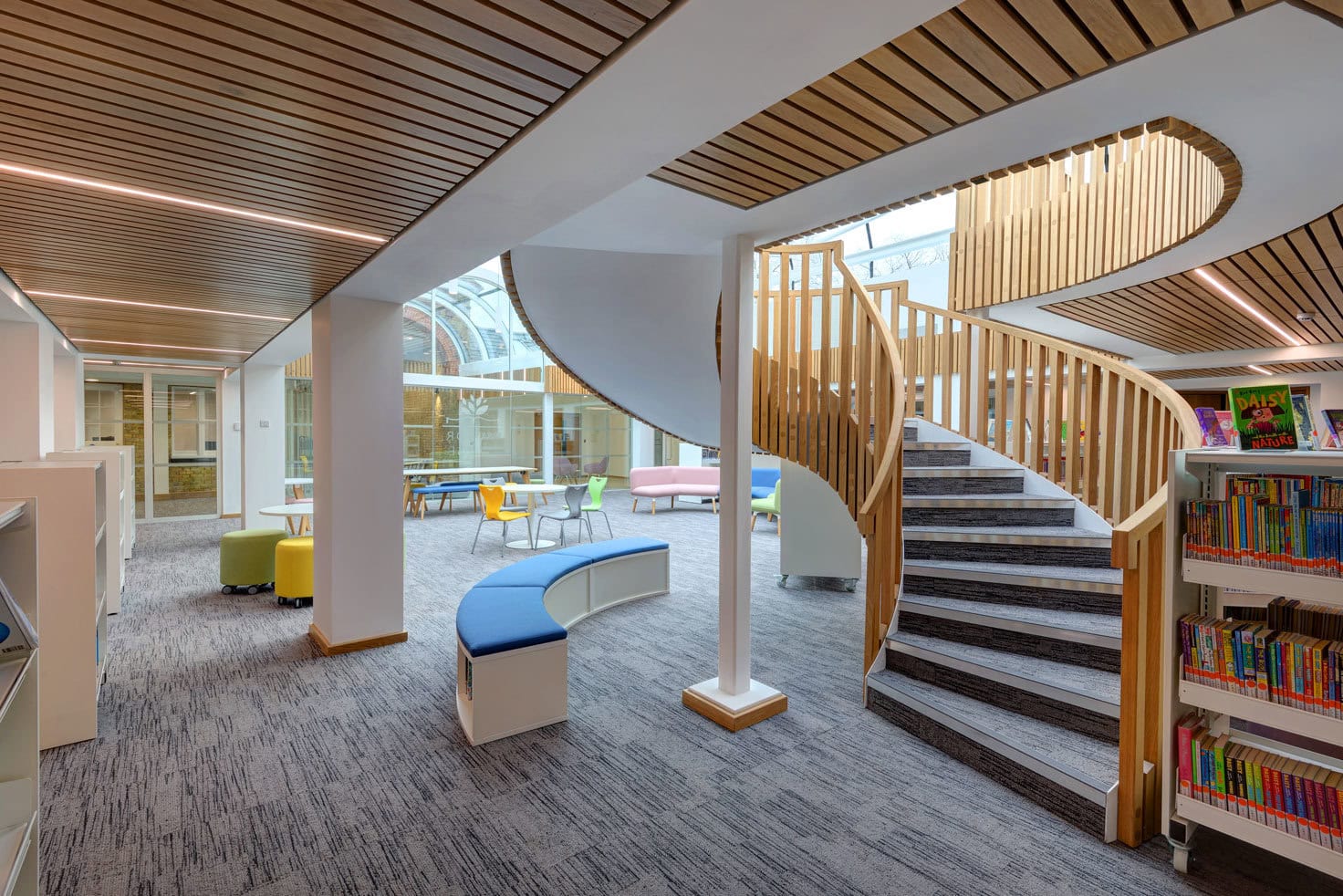 Large curved helical staircase clad in carpet inside school library Manor Lodge School Radlett