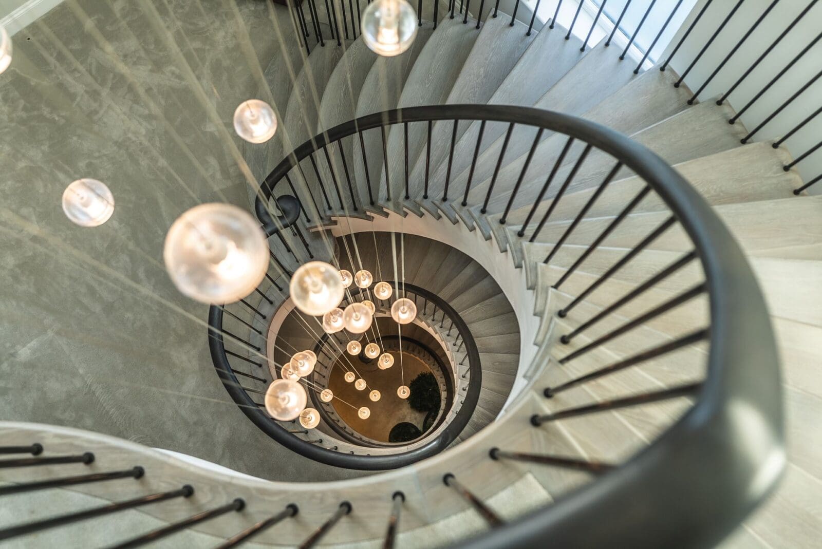 Orb chandelier hanging through three curved luxury staircases