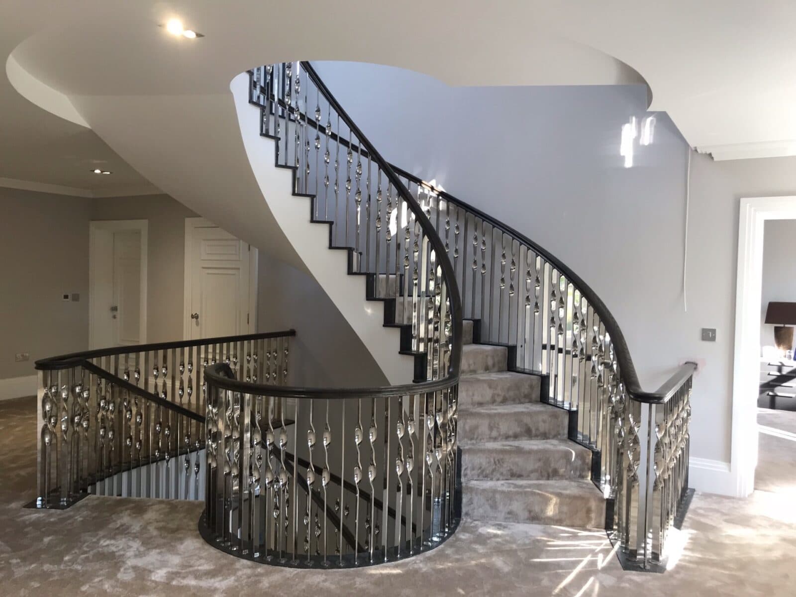 Twin helical staircase with luxurious carpet and bespoke chrome balustrade Greenlea Cedar Road Surrey