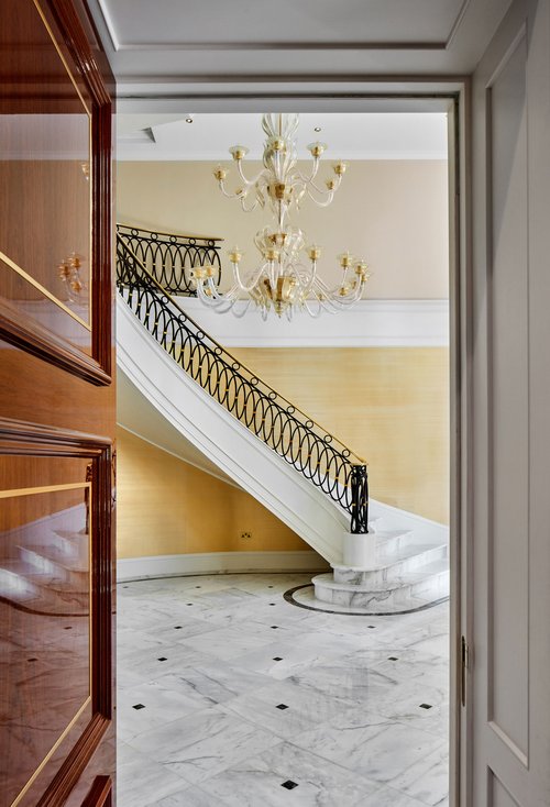 View of helical staircase through an open door with white marble flooring